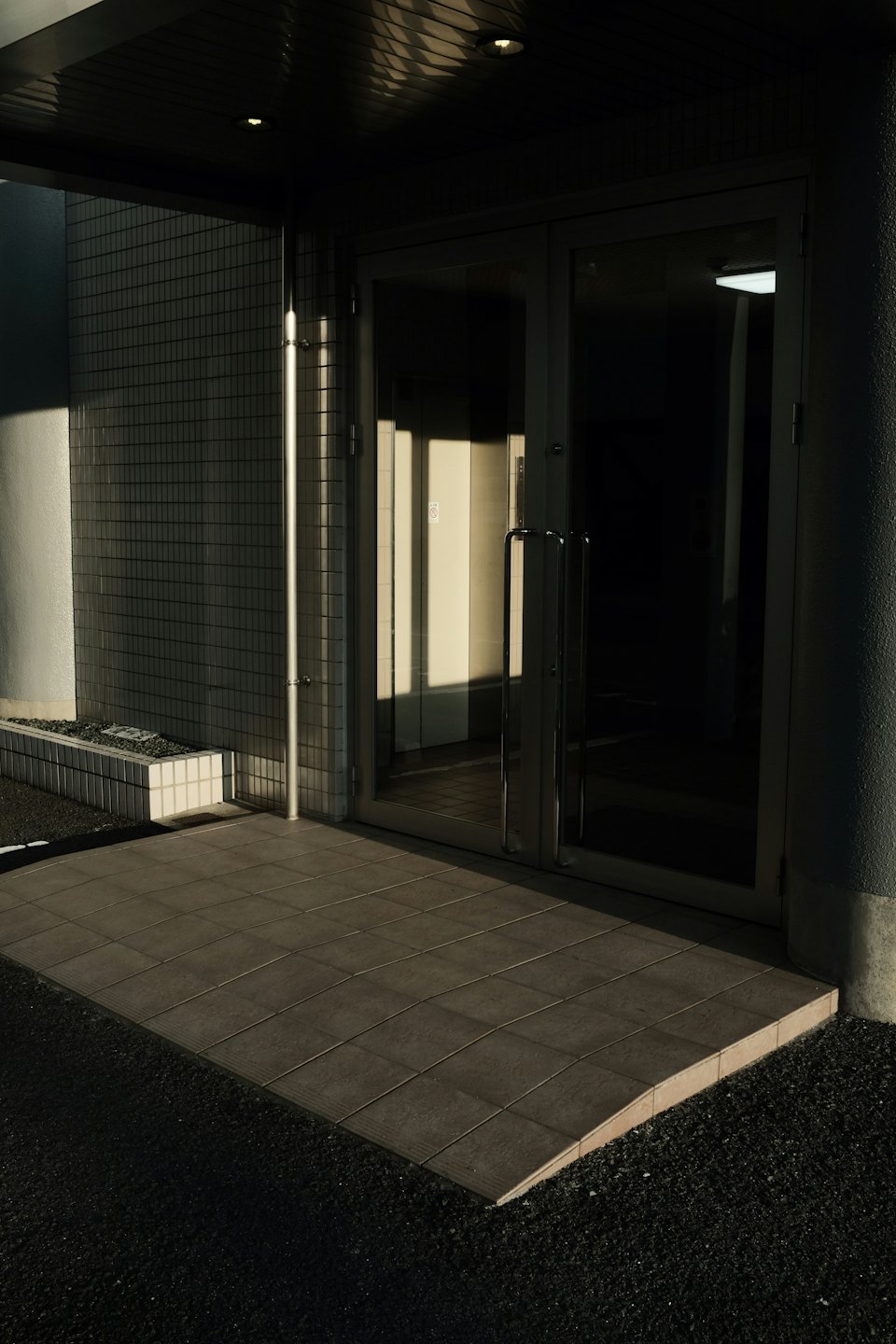 Porte d'ingresso in vetro con rampa che conduce dalla ghiaia.